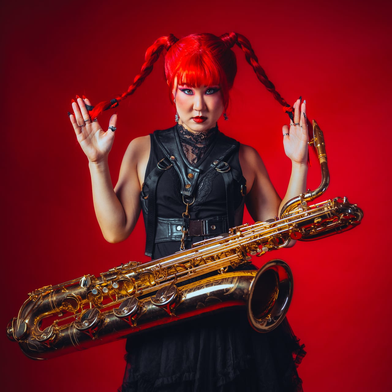 BFS single cover: Grace Kelly with long red braids held up in both hands, a gold baritone saxophone across her body, against a red backdrop